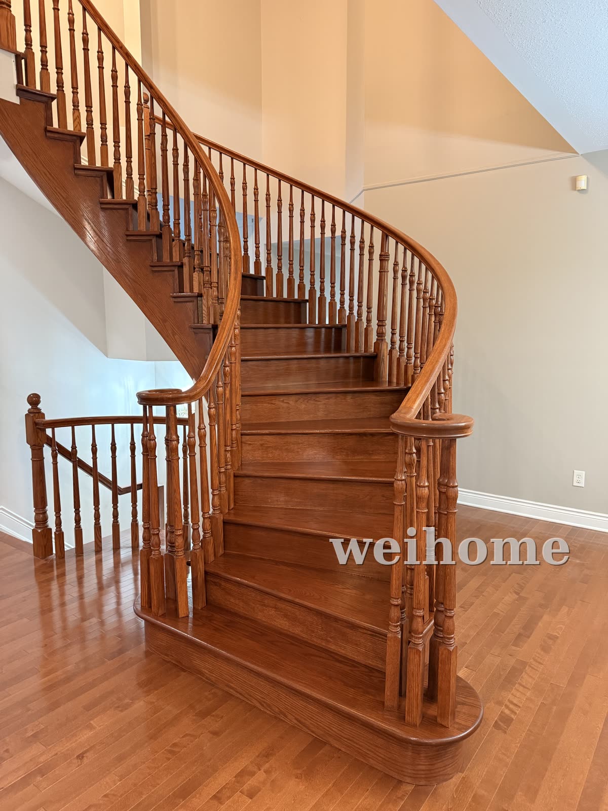 Curved staircase after — new oak treads, stained to match the railing